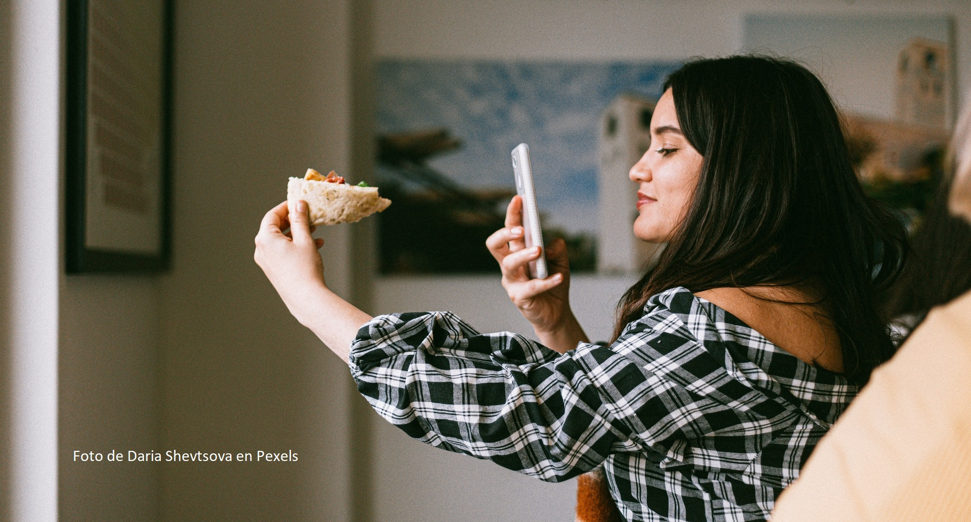 Unha muller fai unha foto cun móbil a un plato de comida