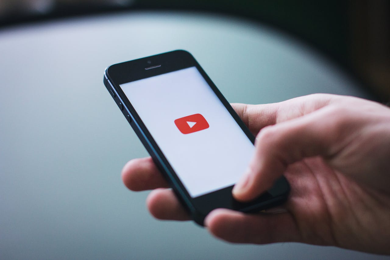 Una mano sostiene un móbil co logo de youtube