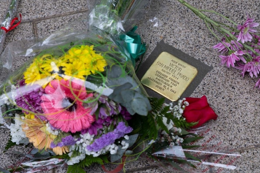 fotografía dun ramo de flores á carón dunha placa commemorativa en memoria de Víctor San Miguel Prado