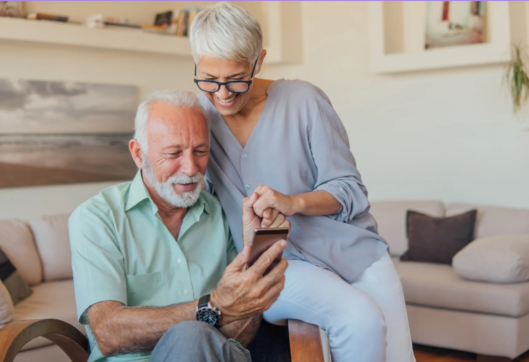 Dos adultos miran un móvil con alegría