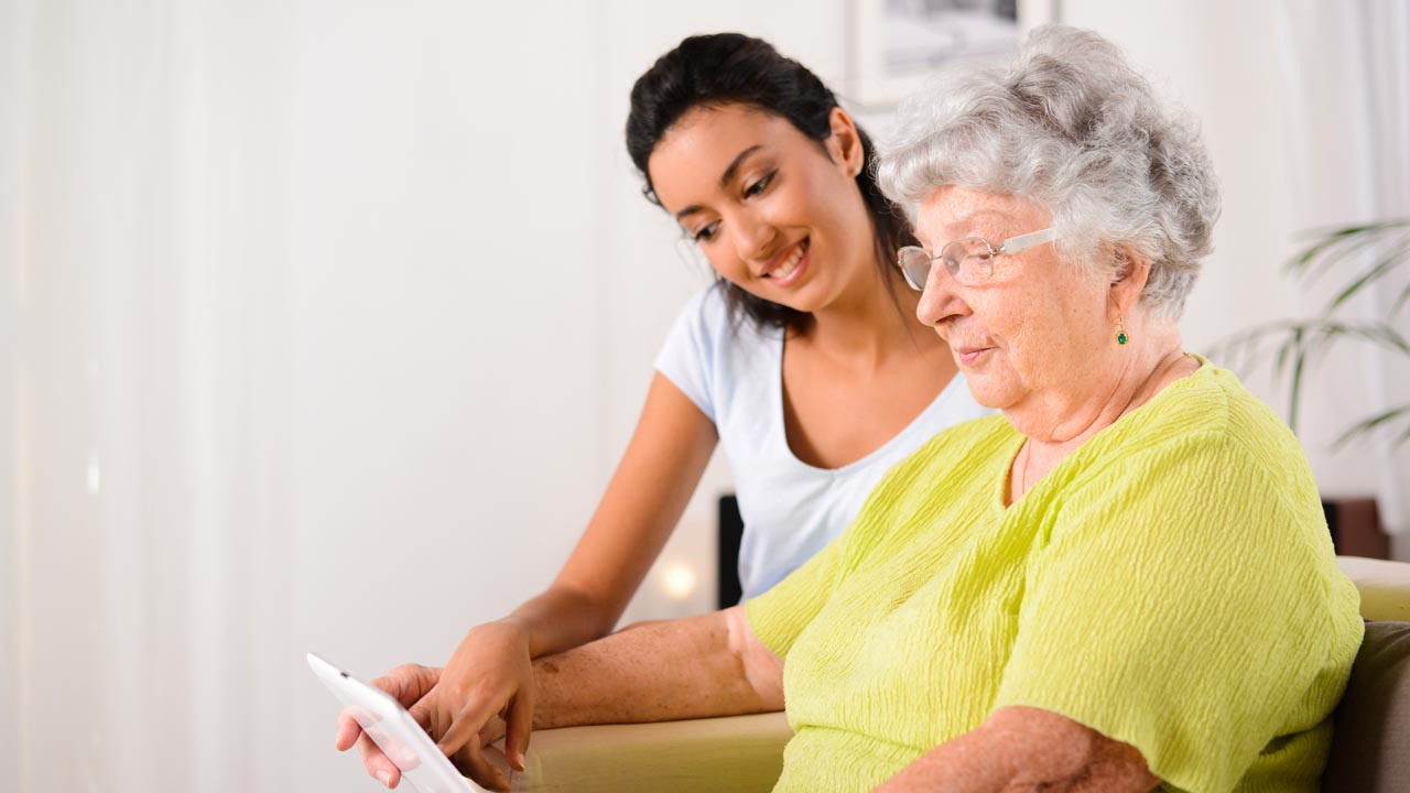 Una mujer madura y una chica joven al lado miran un movil sentadas