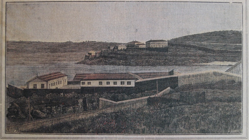 A imaxe mostra un gravado ou ilustración histórica do Lazareto de Oza, na Coruña. Trátase dunha vista panorámica dun complexo sanitario situado xunto ao mar, rodeado por altos muros de peche.  No primeiro plano obsérvanse varios edificios rectangulares con tellados a dúas augas, encerrados dentro dun recinto amurallado. No fondo pode verse outro conxunto de edificacións situado nun pequeno promontorio costeiro. A paisaxe aparece practicamente despoboada, con terreos abertos e ondulados arredor das instalacións.  